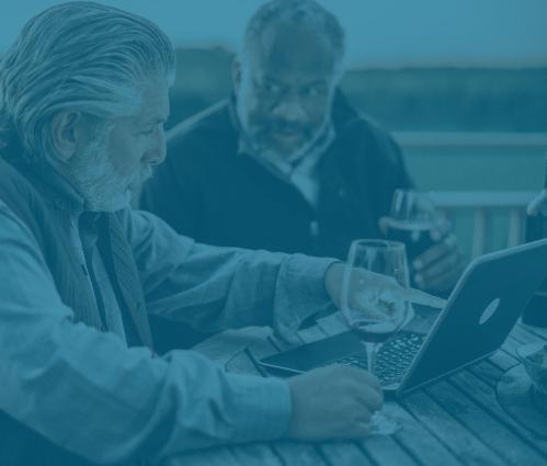 Two men drinking wine and looking at a laptop